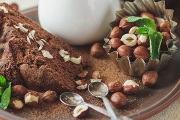 Piece of chocolate cake, mint leaves, hazelnuts and jar with milk