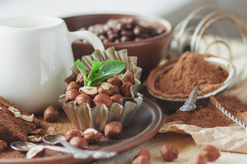 Piece of chocolate cake, mint leaves, hazelnuts and jar with milk