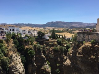 Fototapeta na wymiar View from the Puente Nuevo in the city of Ronda in Andalusia, Spain. The Puente Nuevo is the newest and largest of three bridges that spanned the 120-metre-deep chasm that carries the Guadalevín River
