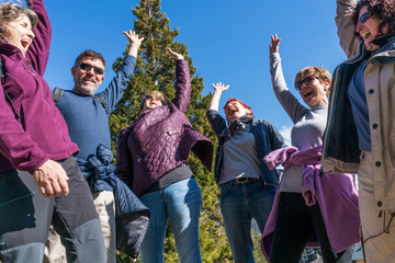 A bunch of friends in their 50's practice mountain hiking at spring time