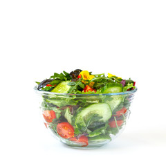 Vegetable salad in a glass bowl with greens, olive oil and sesame  on white isolated background. Vegetarian. Concept for a tasty and healthy meal.