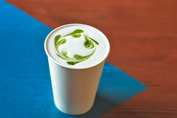matcha latte in a paper Cup isolated on a wooden table