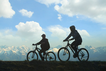 Fototapeta na wymiar Two Cyclists Against Mountain Landscape