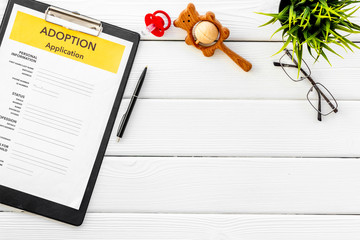 Children care with adoption application, dummy and toy on white wooden background top view space...