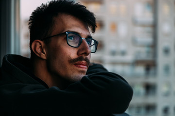 Portrait of a young man looking at sunset from a balcony thinking about life