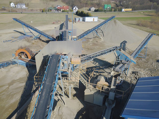 Fototapeta premium Elements of equipment for the extraction and sorting of rubble. Production of construction materials. Metal construction for working with stone and rocks. Slag of gravel under the conveyor belt