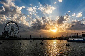Ferris Wheel under Dramatic Sunrise and Sunset and cloudy sky, Nature background with strong sunbeam, Hope concept.