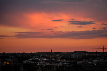 Burning red  sky on rome architecture skyline with working cranes