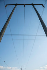 Naklejka premium Electric poles with wires and cables set on a bright blue daylight sky.