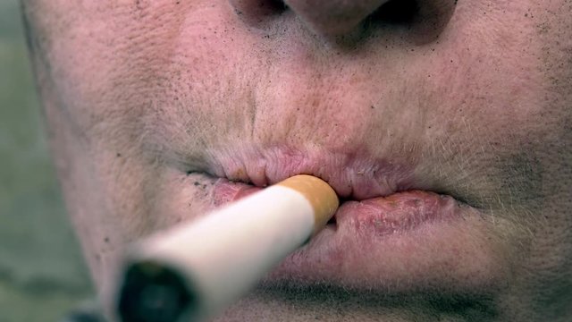 homeless person takes a cigarette in his mouth and lights a cigarette. Close-up.
