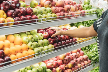 Woman's hand choosing red apple in the supermarket