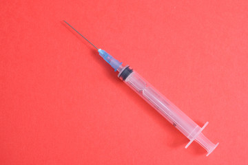 Empty medical syringe on a red background. The concept of dangerous vaccinations. The problem of...