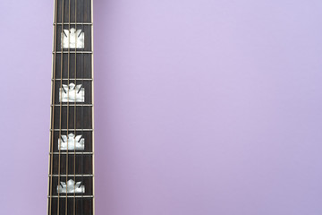 Acoustic guitar neck on the left on purple background. Perspective. Space for text