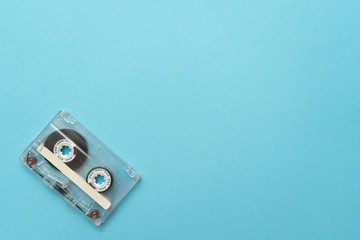 Fototapeta premium Old audio cassette in the left-down corner on blue background. Place for text.