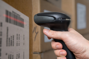 Scanning barcode with bar code reader on packages in warehouse.