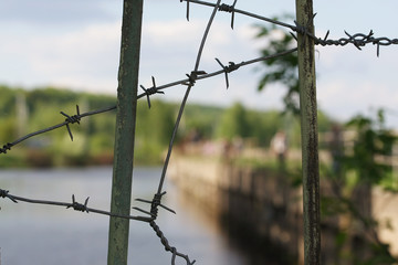 barbed wire on metal parts of fence on blurred background