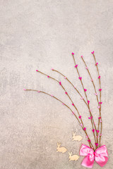 Artificial decorative multicolored willow twigs and wooden figures of bunny. The concept of Easter cards, wallpapers, backgrounds. On a stone background, top view, copy space