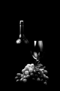 Black White Photo Bottle Of Wine With Glass And Grape On Black Background.