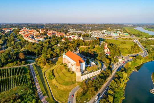 Sandomierz, Poland. Medieval gothic castle in front, old town with town hall tower,  gothic cathedral and Vistula river in the background. Aerial view in sunset light