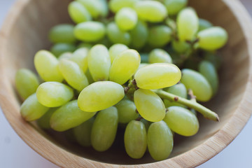 Grapes in a wooden bowl isolated on white background. Green grapes Kish Mish. Top view. 
