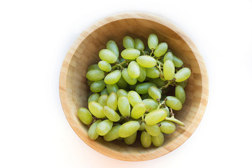 Grapes in a wooden bowl isolated on white background. Green grapes Kish Mish. Top view. 
