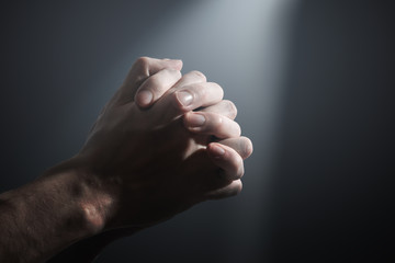 Hands of a prayer.  Light shining on praying man's hands.