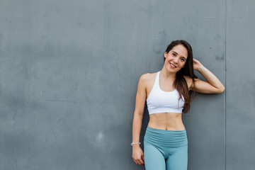 Young beauitful woman wearing sport suit stand on grey background. Smiling yoga teacher.