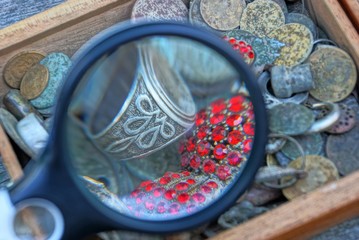 Obraz na płótnie Canvas round magnifier over a pile of old jewels in a box