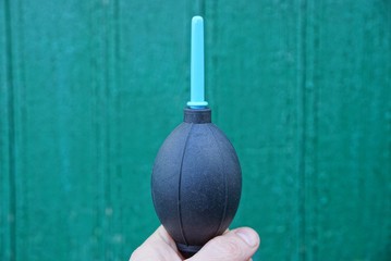 one black plastic pear in his hand on a green background