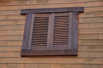 Obraz na płótnie Canvas window covered with brown wooden shutters on the wall of boards
