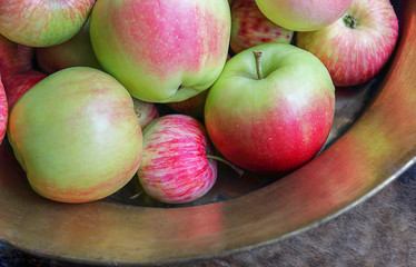 Ripe red apples in a copper bowl. Autumn background. Abundant harvest. Selective focus, top view.