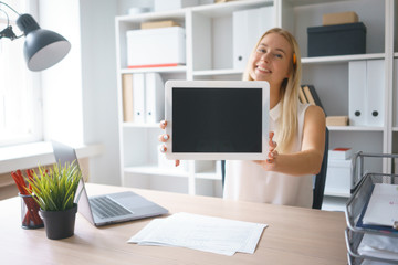 young beautiful woman work on tablet hold show screen sit at table in office smile