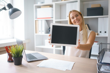 young beautiful woman work on tablet hold show screen sit at table in office smile