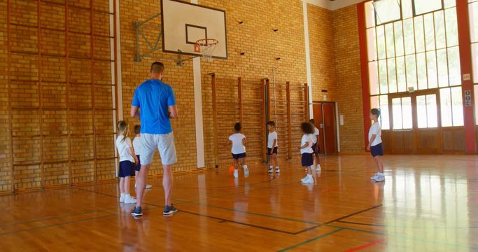 Basketball coach teaching basketball to schoolkids in basketball court 4k