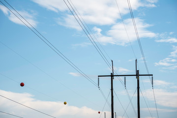 Electric poles with wires and cables set on a bright blue daylight sky.