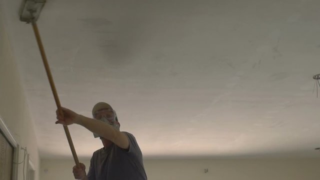 A drywall working sanding a ceiling 