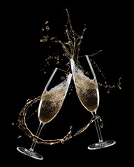 Glasses of champagne clinking together and splashing on black background