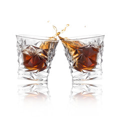 Glasses of expensive whiskey clinking together and splashing on white background