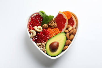 Bowl with products for heart-healthy diet on white background, top view