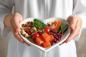 Doctor holding plate with products for heart-healthy diet, closeup