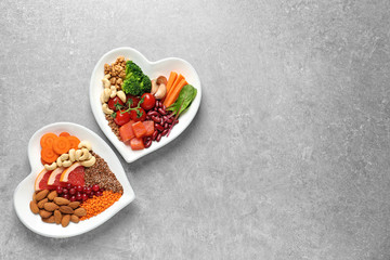 Fototapeta na wymiar Plates with heart-healthy diet products on grey background, top view. Space for text