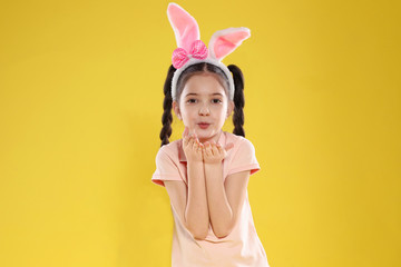 Obraz na płótnie Canvas Portrait of little girl in Easter bunny ears headband on color background