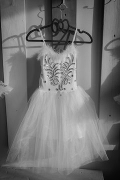 Dress for ballet, tutu, hanging on a hanger on a decorative board with hooks. Black and white photo.