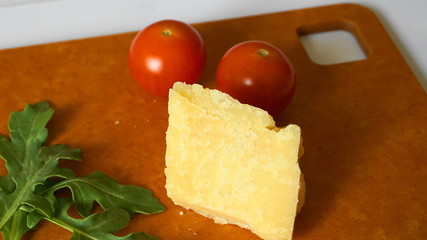 Fresh green arugula leaves, cherry tomatoes and parmesan cheese on hardboard.
