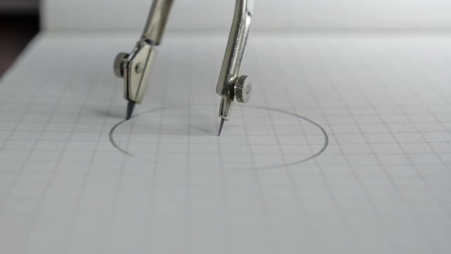 Macro of the compass drawing a circle on paper. Close up