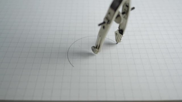Macro of the compass drawing a circle on paper. Close up