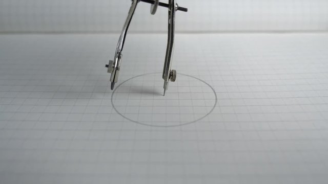Macro of the compass drawing a circle on paper. Close up