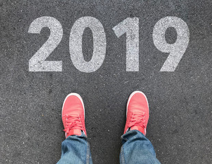 top view of feet and 2019 text on asphalt road , start new year concept