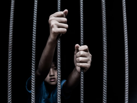 sad child holding a steel cage in old iron bar. children prison and prisoner concept