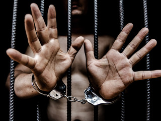 Young man desperate to catch the iron prison,prisoner concept,Handcuffed hands of a prisoner in...